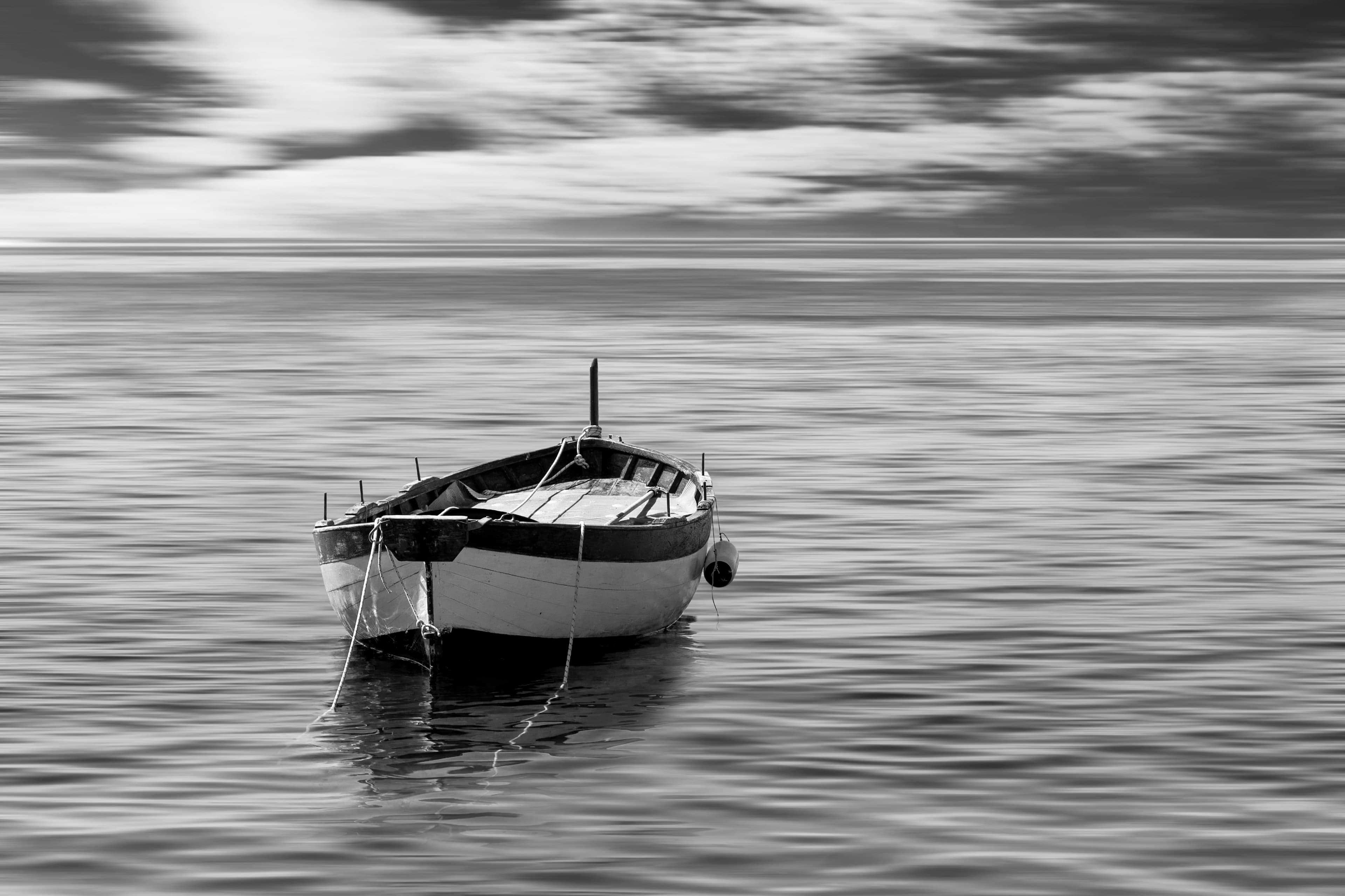 Um pequeno barco ancorado sozinho em mar calmo.
